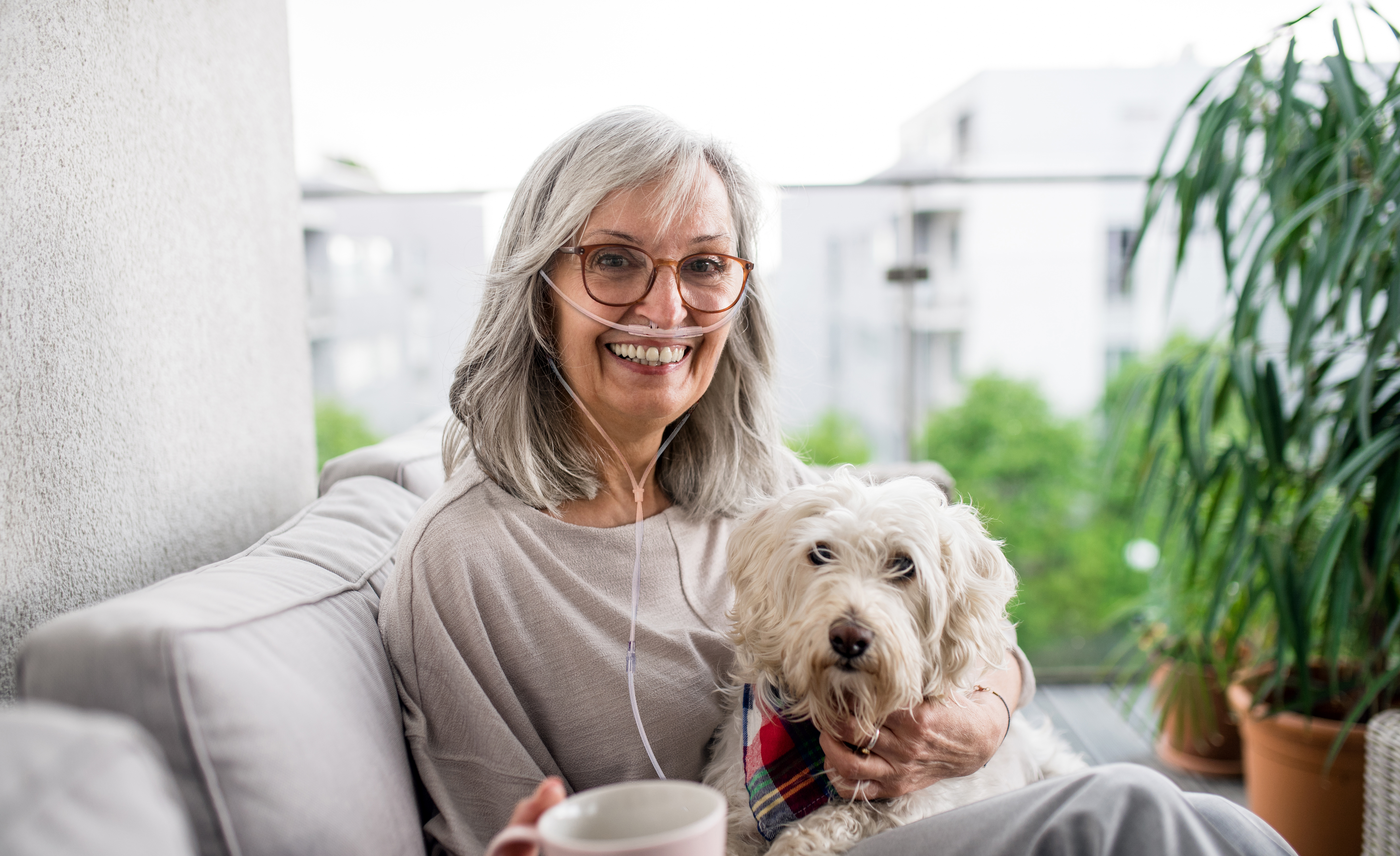 Senior woman with coffee and dog at home, resting outdoors on balcony.